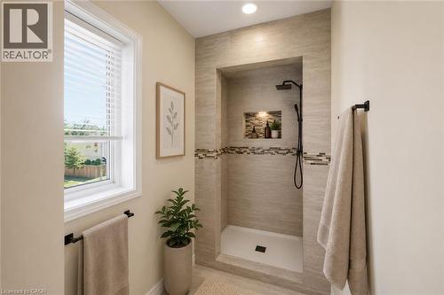 Virtually Staged - Tiled walk-in shower featuring a fixed rain head, handheld sprayer, and recessed shelf with accent lighting - 309 Cope Street, Hamilton, ON - Indoor Photo Showing Bathroom