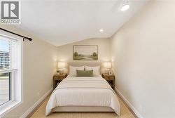 Virtually Staged - Bedroom featuring wood-finish flooring, two paneled doors, a window with horizontal blinds, and a ceiling with recessed and track lighting - 
