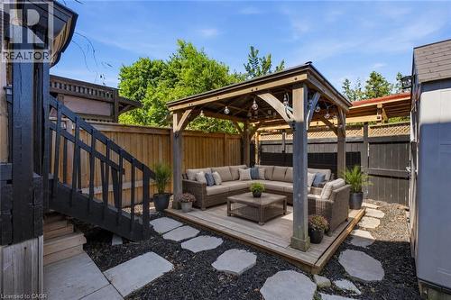 Private backyard retreat featuring a wood pergola over a wood-finish deck, stone pavers, and dark ground cover - 309 Cope Street, Hamilton, ON - Outdoor