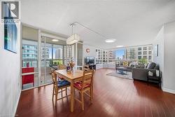Open-concept living area with wood-finish flooring, featuring a dedicated dining space and a sunroom with sliding glass doors - 