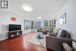 Living area featuring rich wood-finish flooring, white walls, and a multi-pane window wall - 