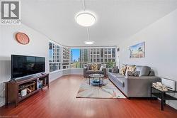 Spacious living area featuring wood-finish flooring, white walls, and contemporary ceiling light fixtures - 