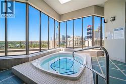Indoor spa tub with full-height windows overlooking a city skyline - 