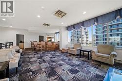 Lounge area featuring a built-in bar with bar stools, patterned carpet flooring, recessed lighting, and expansive windows showcasing urban architecture - 