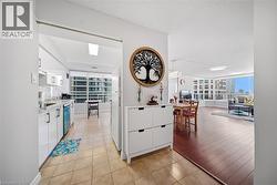 Bright kitchen featuring white cabinetry, light-toned tile flooring, and integrated appliances - 