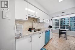 Kitchen featuring white cabinetry, light-toned tiled flooring, and speckled countertops - 
