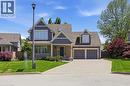 Symmetrical facade featuring a covered front porch with white railings, a stone and siding exterior, a two-car garage, dormer windows, and a paver driveway - 56 Mccaffery Crescent, St. Catharines, ON 
