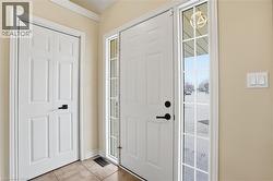 Entryway featuring a paneled door with side-light window, tile flooring, and neutral wall paint - 
