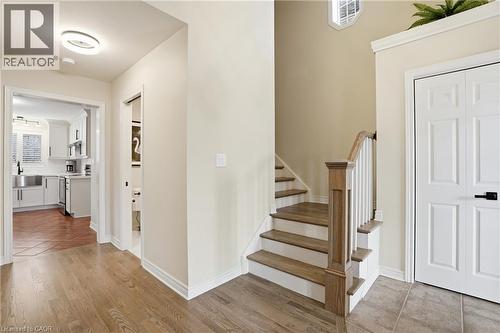 Entryway featuring wood-finish flooring, a staircase with wood-finish treads and white risers, and a paneled double door with matte black hardware - 56 Mccaffery Crescent, St. Catharines, ON 