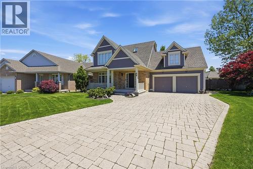 Contemporary home exterior featuring a paver driveway, two-car garage, covered porch, dormer windows, and a landscaped front yard - 56 Mccaffery Crescent, St. Catharines, ON 