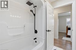 Bathtub and shower combination featuring a matte black shower system with rain shower head and handheld sprayer - 