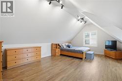 Room featuring sloped ceilings, track lighting, and wood-finish flooring - 
