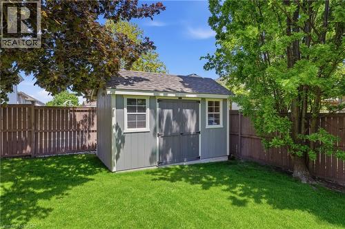 Backyard featuring a gray storage shed with white trim and a shingled roof, set against a wood fence - 56 Mccaffery Crescent, St. Catharines, ON 
