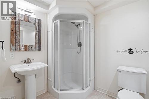 Bathroom featuring a corner shower enclosure, pedestal sink with a chrome faucet, and a wall-mounted mirror with a distressed wood frame - 56 Mccaffery Crescent, St. Catharines, ON 