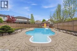 Expansive backyard featuring a large swimming pool with a stone coping, surrounded by a paver patio - 