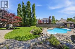Expansive backyard featuring a freeform swimming pool with integrated steps, surrounded by paver patio hardscaping - 