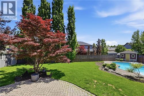 Expansive backyard featuring a large swimming pool, paver patio, lush green lawn, and two garden sheds - 56 Mccaffery Crescent, St. Catharines, ON 