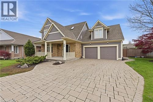 Two-story residence featuring a brick and siding facade, a covered front porch with white railings, a paver driveway, and a two-car garage - 56 Mccaffery Crescent, St. Catharines, ON 
