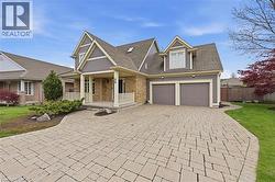 Two-story residence featuring a brick and siding facade, a covered front porch with white railings, a paver driveway, and a two-car garage - 