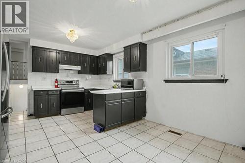 Kitchen featuring dark cabinetry, white countertops, a stainless steel range, and a white tile backsplash - 396 Pinemeadow Avenue, Mississauga, ON 