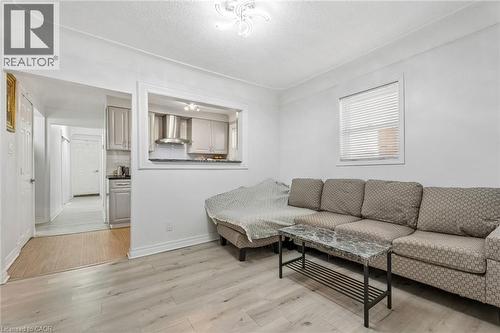 Living area featuring light wood-finish flooring, white walls, and a recessed pass-through window to the kitchen - 43 Whitfield Avenue, Hamilton, ON 