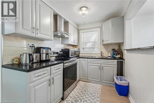 Kitchen with light-toned cabinetry, dark countertops, and a tile backsplash - 43 Whitfield Avenue, Hamilton, ON 