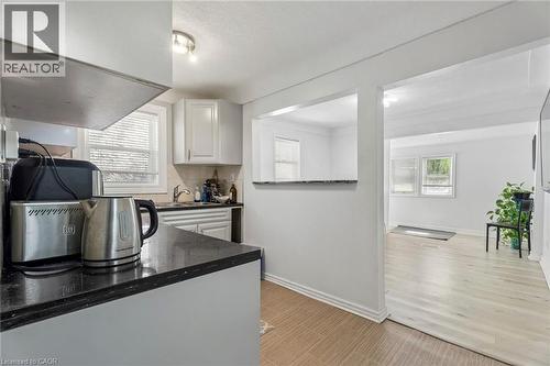 Kitchen featuring white cabinetry, dark speckled countertops, and a tile backsplash - 43 Whitfield Avenue, Hamilton, ON 