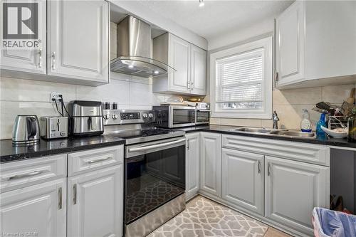 Kitchen featuring white shaker-style cabinetry, dark speckled countertops, and a stainless steel appliance suite - 43 Whitfield Avenue, Hamilton, ON 