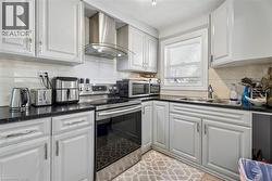 Kitchen featuring white shaker-style cabinetry, dark speckled countertops, and a stainless steel appliance suite - 