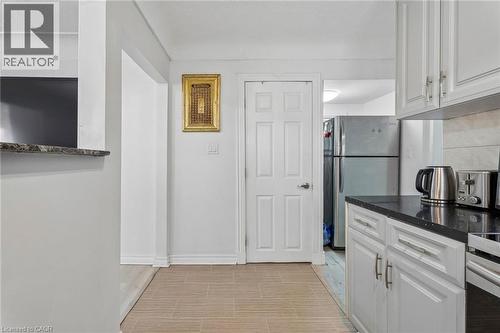 Kitchen featuring white cabinetry with silver hardware, black countertops, and a tile backsplash - 43 Whitfield Avenue, Hamilton, ON 