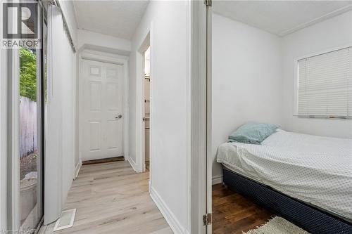 Light-toned wood-finish flooring in the hallway leading to a four-panel door - 43 Whitfield Avenue, Hamilton, ON 