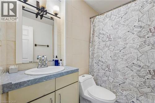 Bathroom featuring a vanity with a white oval sink and chrome faucet, a grey patterned countertop, and light-toned cabinetry - 43 Whitfield Avenue, Hamilton, ON 