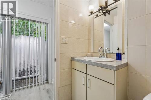 Bathroom vanity featuring a single basin sink and a mirror with an overhead light fixture - 43 Whitfield Avenue, Hamilton, ON 