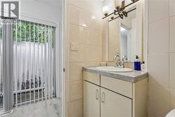 Bathroom vanity featuring a single basin sink and a mirror with an overhead light fixture - 