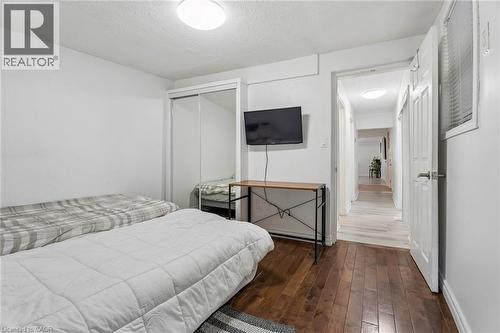 Bedroom featuring dark wood-finish flooring, white walls, and a white ceiling with a flush-mount light fixture - 43 Whitfield Avenue, Hamilton, ON 