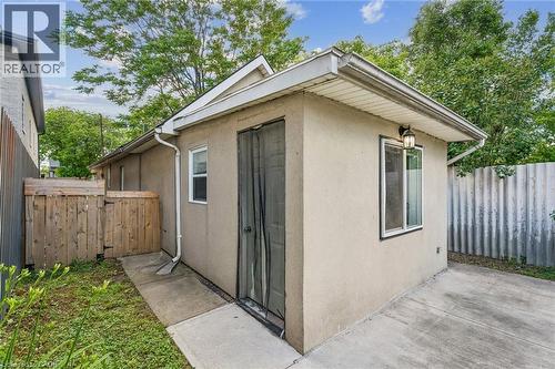 Exterior structure featuring stucco siding, white-trimmed window, and an outdoor wall-mounted light fixture - 43 Whitfield Avenue, Hamilton, ON 