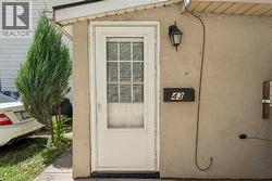 Entryway featuring a white paneled door with window inserts, stucco exterior, and an exterior wall light fixture - 