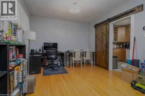 Warm-toned wood flooring extends through this room, featuring a dark wood barn door - 98 Brubacher Street, Kitchener, ON 
