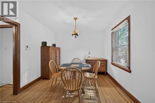 Brightly lit room featuring wood-finish flooring, a window with horizontal blinds, and a brass-tone chandelier - 83 Aberfoyle Avenue, Hamilton, ON 
