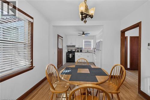 Hardwood-style flooring extends through a dining area with a decorative chandelier - 83 Aberfoyle Avenue, Hamilton, ON 