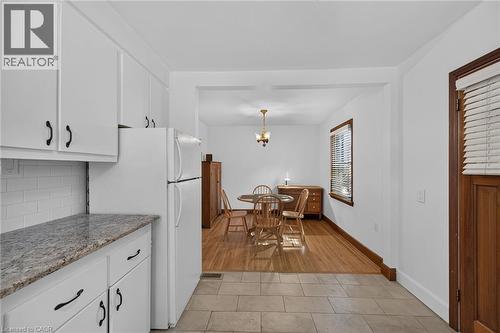 Kitchen featuring white cabinetry, granite-finish countertops, and subway tile backsplash - 83 Aberfoyle Avenue, Hamilton, ON 