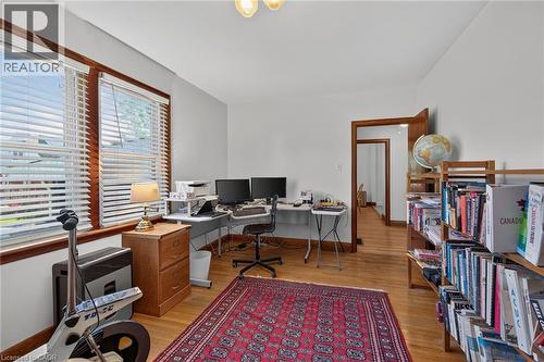 Bright room featuring wood-finish flooring, two large windows with blinds, a built-in wooden bookshelf, and a doorway with wood trim - 83 Aberfoyle Avenue, Hamilton, ON 