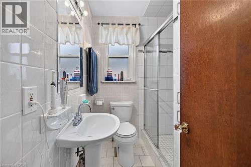 Bathroom featuring a pedestal sink, chrome faucet, and a wall-mounted mirror with overhead lighting - 83 Aberfoyle Avenue, Hamilton, ON 