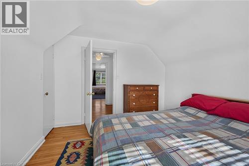 Attic bedroom featuring hardwood flooring, white walls, and a sloped ceiling - 83 Aberfoyle Avenue, Hamilton, ON 