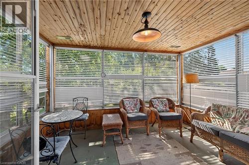 Enclosed sunroom featuring a natural wood-finish plank ceiling, multiple windows with blinds, and a built-in ceiling light fixture - 83 Aberfoyle Avenue, Hamilton, ON 