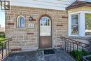 Stone facade entry featuring an arched door with glass lites, a rounded arch window, and a bay window with a shingle roof detail - 83 Aberfoyle Avenue, Hamilton, ON 