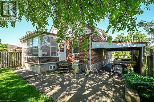 Exterior showcasing a brick facade, an enclosed sunroom with large windows, and a covered carport - 83 Aberfoyle Avenue, Hamilton, ON 