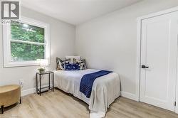 Bedroom featuring light wood-finish flooring, a white trim window, and a white interior door with matte black hardware - 