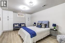 Spacious room featuring light wood-finish flooring, recessed ceiling lighting, and two built-in white cabinetry units with black handles - 
