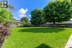 Spacious green lawn surrounded by mature trees and a wooden fence - 
